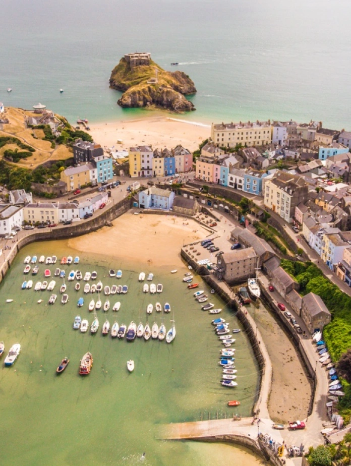 Aerial view of a harbour, two beaches and pastel coloured houses.